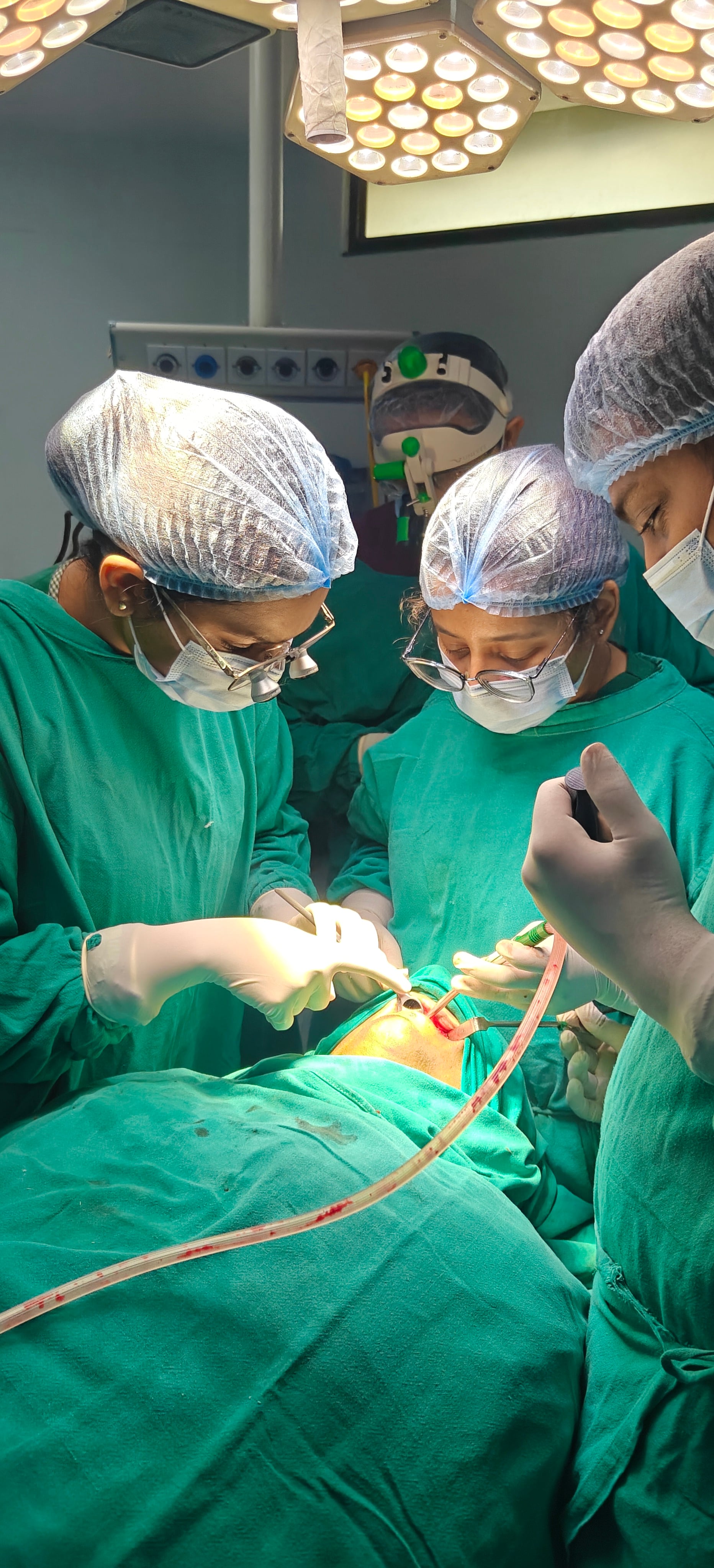 Dr. Bhavya Soni performing oral surgery under surgical lights with team